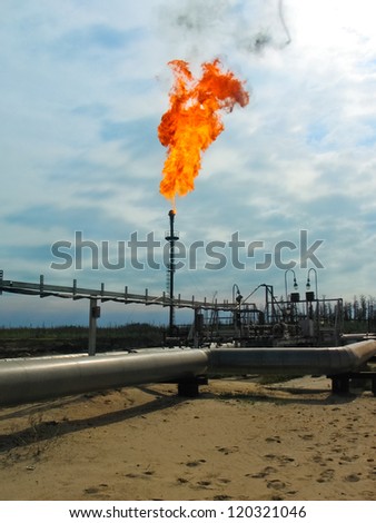 Burning oil gas flare over the blue sky