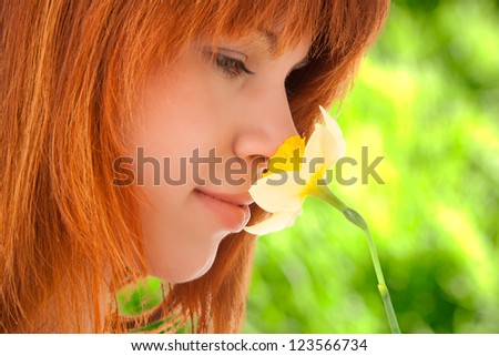 Woman smelling yellow narcissus in the hand outdoors
