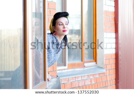 Beautiful woman with pin-up make-up and hairstyle looking in window