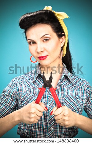 Pin-up girl in check shirt with pliers on blue background