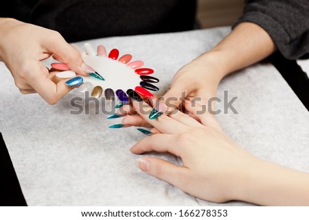 Woman at nail studio chosing color of nail polish
