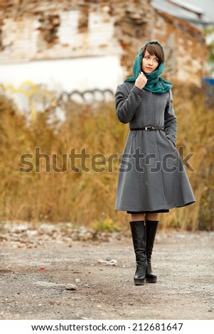 Beautiful alone woman  in grey coat walking on strange house