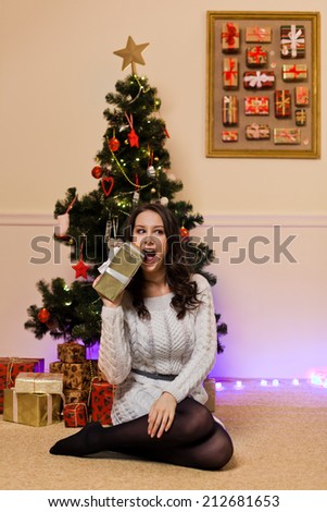 Happy cheerful woman with gifts near christmas tree