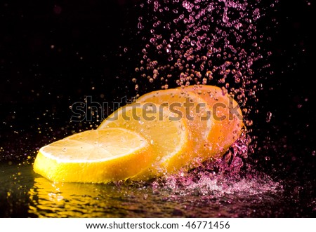 Cut lemon under colorful water splashes