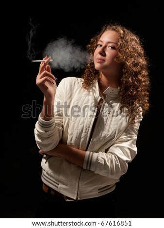Beautiful woman standing and smoking on the black background