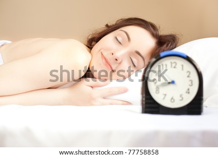 Woman sleeping in bed and alarm-clock  (focus on woman)