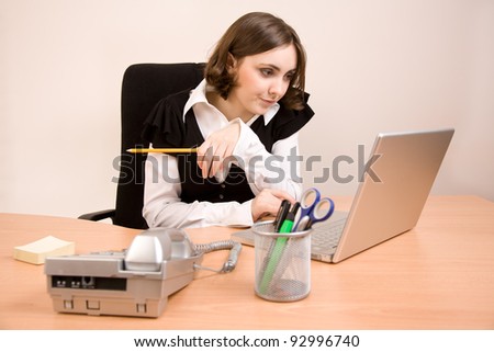 Young secretary with telephone, laptop and pencil working at office