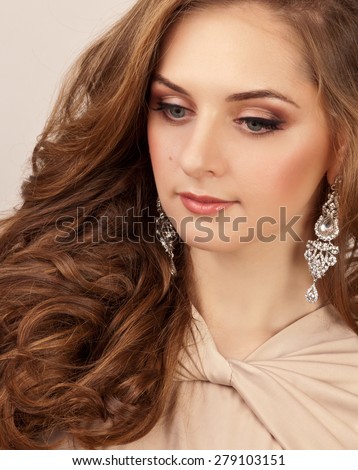 Beautiful woman with silver earrings and makeup looking down