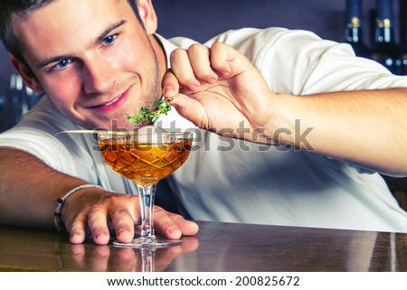 Barman Serving Drinks In Nightclub.Young barkeeper preparing drink.