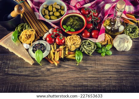 Italian and Mediterranean food ingredients on old wooden background.spaghetti olives basil cherry tomato pesto pasta garlic pepper olive oil and mortar.