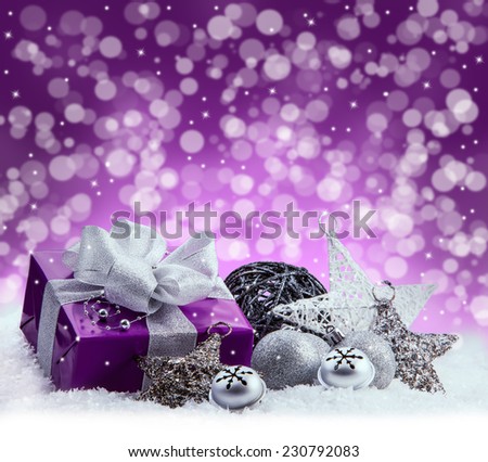 Purple Christmas package , gift of a silver ribbon. Jingle bells , silver christmas balls and christmas stars put on snow. Abstract multicolored blurred background space.