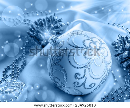 Christmas decoration. Christmas ball, pine cones, glittery jewels on white satin.Blue background.
