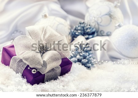 Purple Christmas gift,package with a silver ribbon and background christmas decoration - Christmas balls pine cone white satin and white snow - snowflakes.Christmas time.
