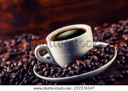 Cup of black coffee and spilled coffee beans. Coffee break