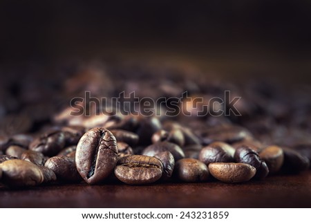 Roasted coffee beans spilled freely on a wooden table.Coffee time