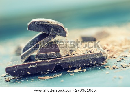 Chocolate. Black chocolate. A few cubes of black chocolate. Chocolate slabs spilled from grated chockolate powder.