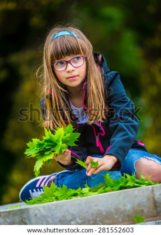 Little girl playing the green maple leaf. In the hands of a bunch of green maple leaf. Happy and fun young girl