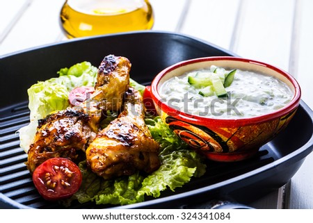 Grilling. Grilled chicken. Grilled chicken legs. Grilled chicken legs, lettuce and cherry tomatoes. Traditional cuisine. Mediterranean cuisine.