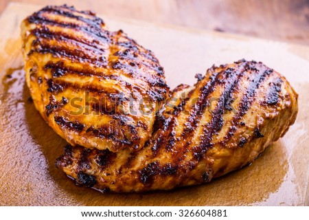 Grilled chicken breast in different variations with cherry tomatoes, green French beans, garlic, herbs, cut lemon on a wooden board or teflon pan. Traditional cuisine. Grill kitchen.