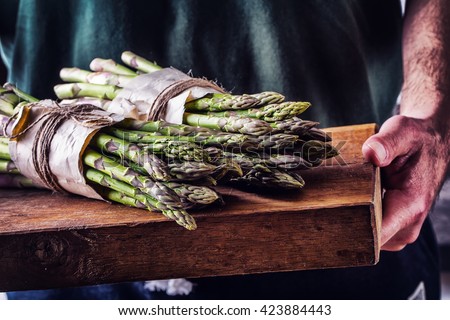 Asparagus. Raw asparagus. Fresh Asparagus.Green Asparagus. Tied asparagus in other positions. Farmer carries tied asparagus on a wooden board.