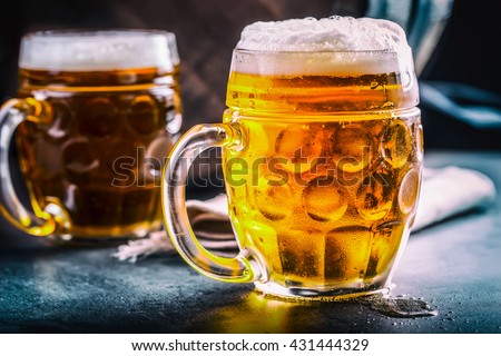 Beer. Two cold beers. Draft beer. Draft ale. Golden beer. Golden ale. Two gold beer with froth on top. Draft cold beer in glass jars in pub hotel or restaurant. Still life.