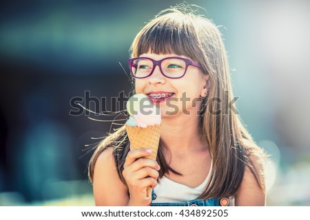 Girl. Teen. Pre teen. Girl with ice cream. Girl with glasses. Girl with teeth braces. Young cute caucasian blond girl wearing teeth braces and glasses. Portrait of a smiling young girl.