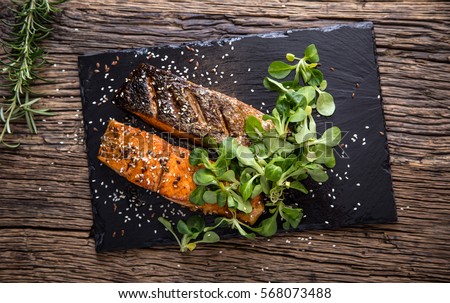 Salmon fillets. Grilled salmon, sesame seeds herb decoration on vintage pan or black slate board. fish roasted on an old wooden table.Studio shot.