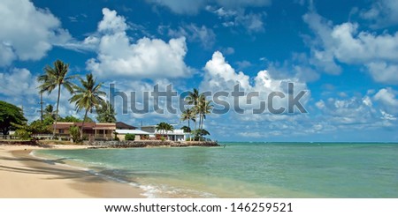 Luxury house on untouched sandy beach with palms trees and azure ocean in background panorama