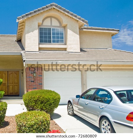 New American dream home with a beautiful blue sky in background and brand new car parked outside.