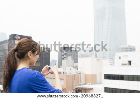 Women to operate the smart phone on the roof of an office building