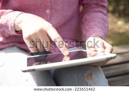 Woman to operate the tablet device sitting on a bench
