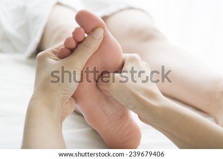 The woman doing foot massage in aesthetic salon