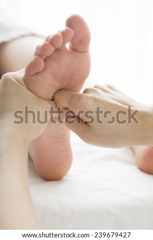 The woman doing foot massage in aesthetic salon