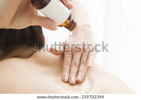 The woman is applying aroma oil on a back