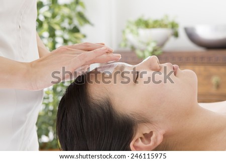 The esthetician applying beauty mask a female face