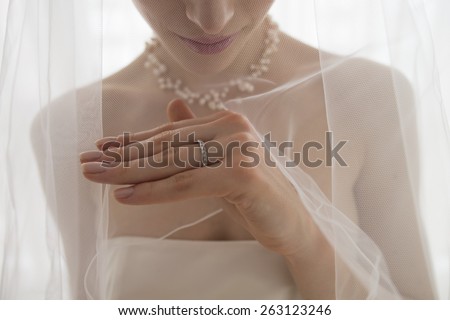Beautiful bride in off shoulder dress looking at wedding ring over white background