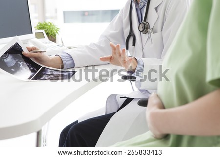 Consultation of young pregnant woman with her doctor - indoors