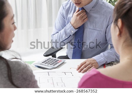 Home, design and architecture concept - woman looking at blueprint of their new house at office