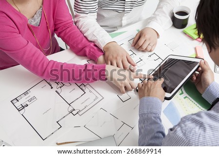 Real-estate agent shows a build project on a digital tablet to a young couple