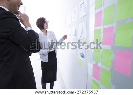 Creative business team looking at sticky notes on wall