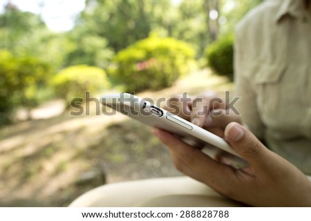 Business woman using mobile smart phone in the park