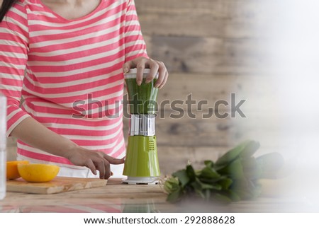 Beautiful Young Woman Making vegetables Smoothie in blender