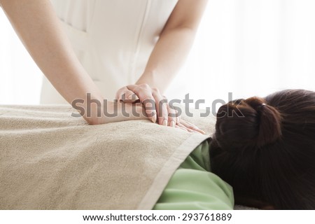 Total relaxation. Beautiful young woman lying on front and  while massage therapist massaging her shoulders