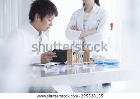 Attractive young female research scientist and her post doctoral male supervisor looking at the tablet in the life science laboratory.