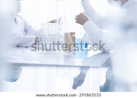 Young scientists with pipette and flask making test or research in clinical laboratory