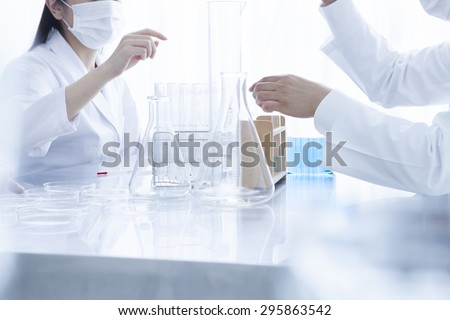 Close up of young scientists with pipette and flasks making test or research in clinical laboratory