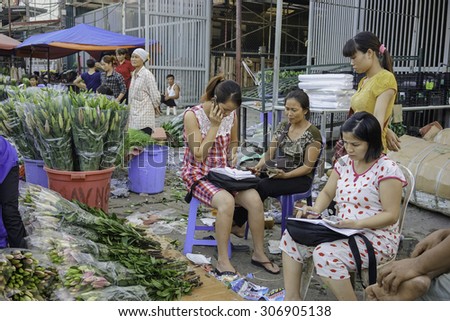 09 July 2015 in Hanoi Vietnam, women florist caculated after selling in Flower market in Hanoi Vietnam