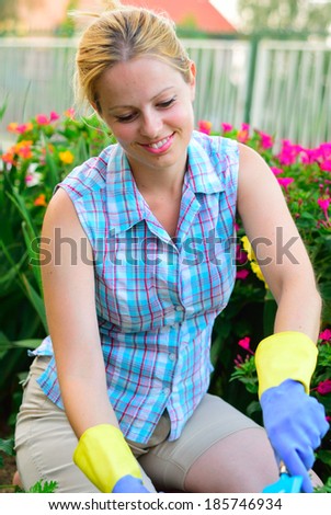 Pretty young woman working in a flower garden, natural model, natural lighting