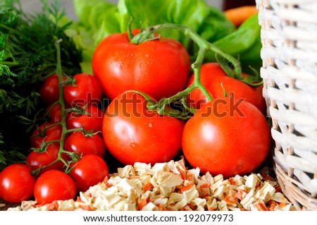 Closeup of vegetable groceries on the wooden kitchen table - tomatoes, cherry tomatoes, carrots and lettuce, selective focus
