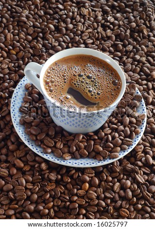 Cup of hot coffee amidst the huge pile of coffee beans